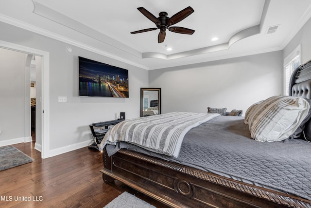bedroom featuring a raised ceiling, hardwood / wood-style floors, recessed lighting, baseboards, and ornamental molding