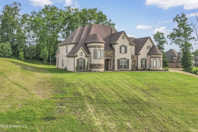 french country inspired facade with a front yard and brick siding