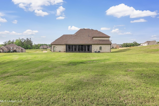 rear view of house featuring a sunroom, a lawn, and a shingled roof