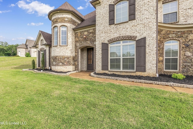 french country inspired facade with brick siding, a front lawn, roof with shingles, and stone siding