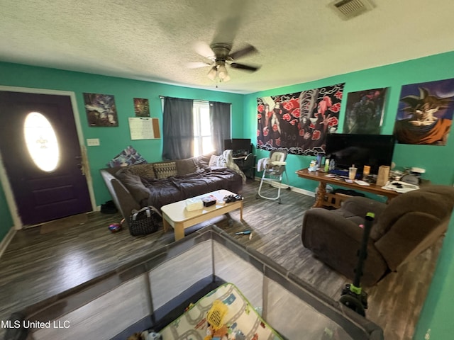 living area featuring wood finished floors, a ceiling fan, a textured ceiling, visible vents, and baseboards