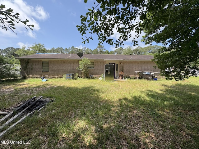 back of house featuring central air condition unit, brick siding, and a lawn