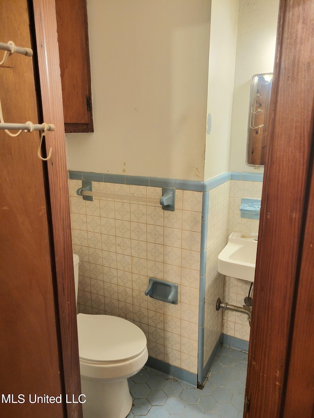 bathroom with tile walls, sink, toilet, and tile patterned floors