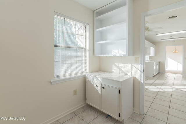 kitchen featuring built in shelves, ceiling fan, white cabinets, and light tile patterned floors