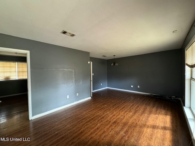 unfurnished room with dark hardwood / wood-style flooring and a notable chandelier