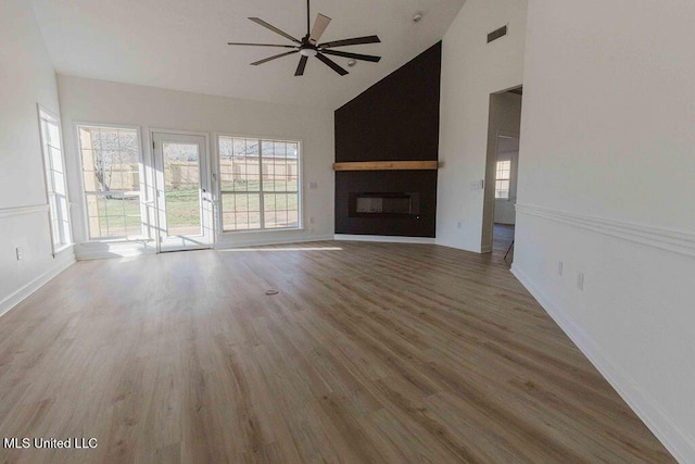 unfurnished living room featuring high vaulted ceiling, a wealth of natural light, a fireplace, and visible vents