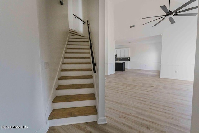 stairway with ceiling fan, wood finished floors, and visible vents