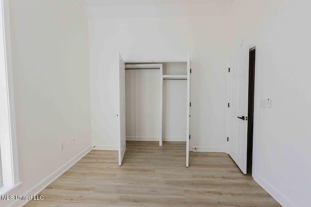 unfurnished bedroom with light wood finished floors, a closet, and baseboards