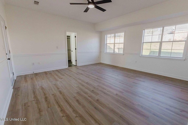 spare room featuring light wood-style flooring, visible vents, ceiling fan, and baseboards