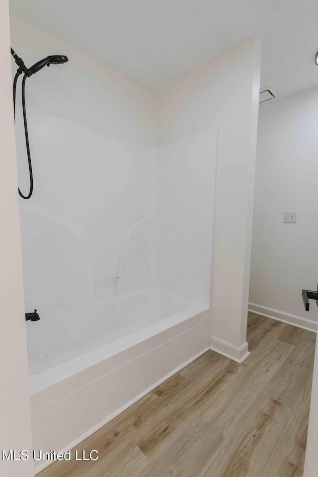 full bathroom featuring shower / washtub combination, wood finished floors, and baseboards