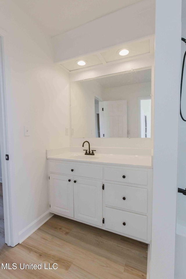 bathroom with recessed lighting, baseboards, wood finished floors, and vanity