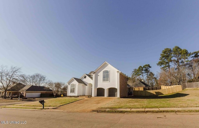 view of front of house with stucco siding, an attached garage, fence, driveway, and a front lawn