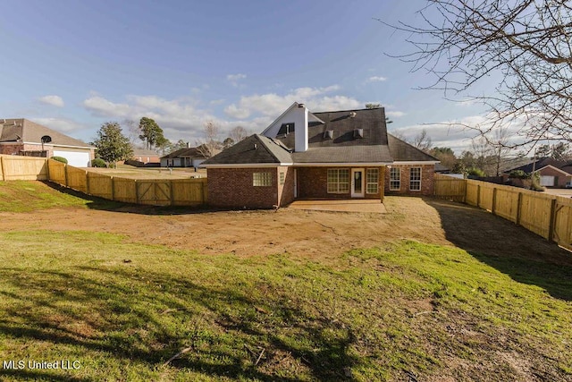 rear view of house with brick siding, a fenced backyard, a patio area, and a yard