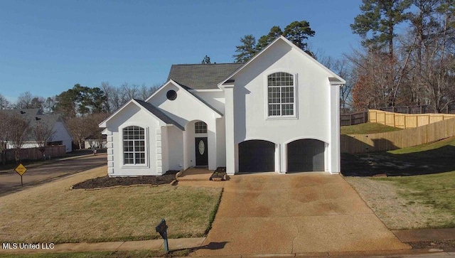 view of front of house featuring a garage, concrete driveway, fence, a front lawn, and stucco siding