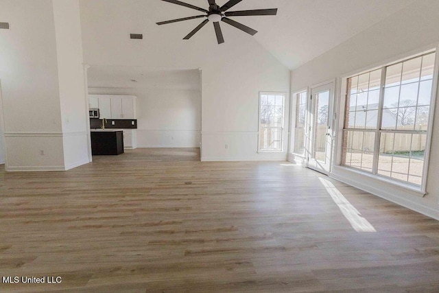 unfurnished living room with visible vents, baseboards, a ceiling fan, wood finished floors, and high vaulted ceiling