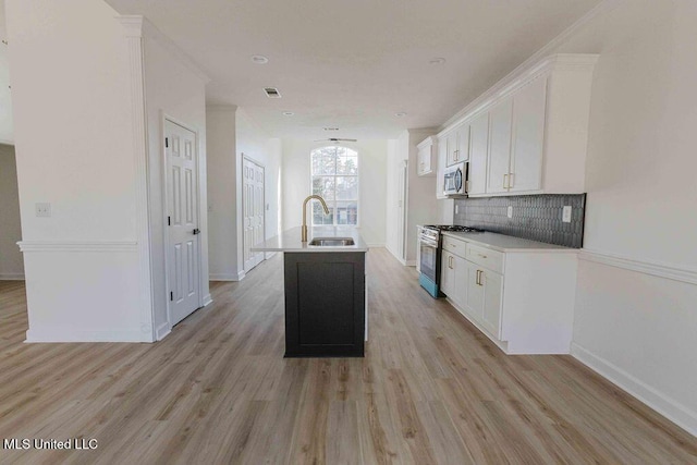 kitchen with white cabinets, a kitchen island with sink, appliances with stainless steel finishes, and light countertops