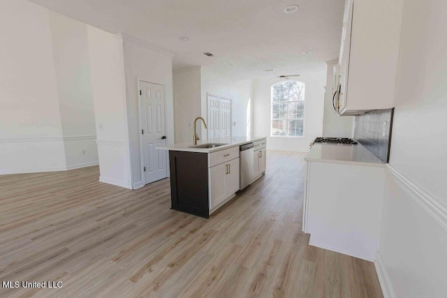 kitchen with a sink, white cabinetry, light countertops, light wood-type flooring, and a center island with sink