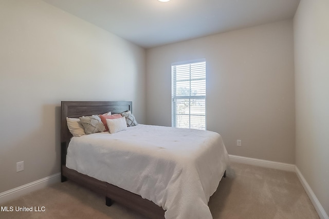 bedroom featuring light carpet and baseboards