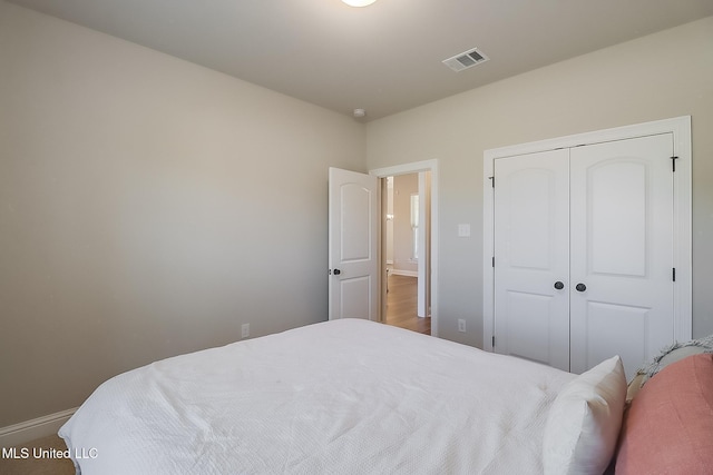 bedroom featuring baseboards, visible vents, and a closet