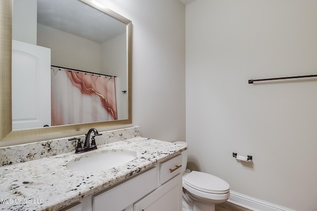 bathroom with vanity, toilet, and baseboards