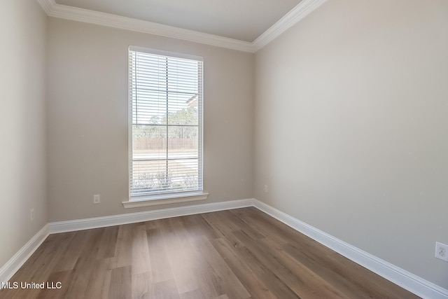 spare room featuring baseboards, wood finished floors, and ornamental molding