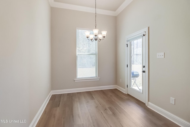 unfurnished dining area featuring baseboards, ornamental molding, wood finished floors, and a healthy amount of sunlight