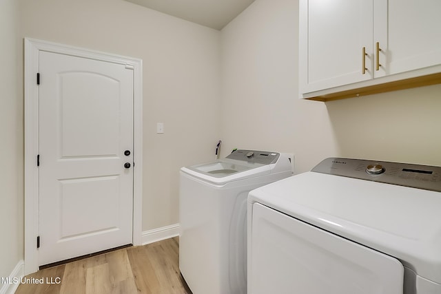 laundry area featuring light wood-type flooring, washing machine and dryer, cabinet space, and baseboards