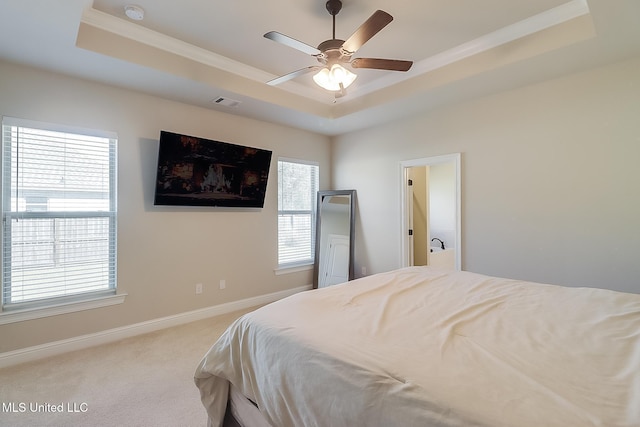 carpeted bedroom featuring baseboards, visible vents, a ceiling fan, a tray ceiling, and crown molding