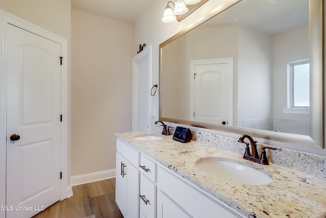 full bathroom featuring double vanity, a sink, baseboards, and wood finished floors