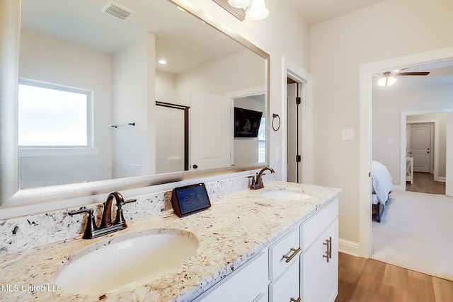 ensuite bathroom featuring connected bathroom, visible vents, a sink, and wood finished floors