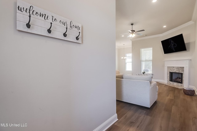 living room with baseboards, dark wood-style flooring, crown molding, and a high end fireplace