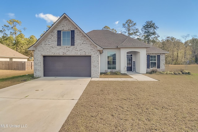 traditional-style house featuring a garage, a front yard, roof with shingles, and driveway