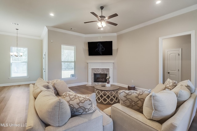 living area with baseboards, ornamental molding, wood finished floors, and a high end fireplace