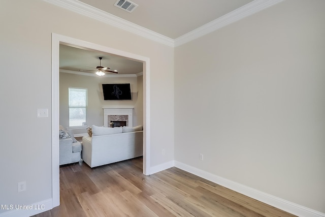 interior space with light wood finished floors, baseboards, visible vents, ornamental molding, and a fireplace