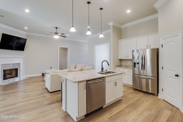 kitchen featuring stainless steel appliances, open floor plan, white cabinets, a sink, and an island with sink