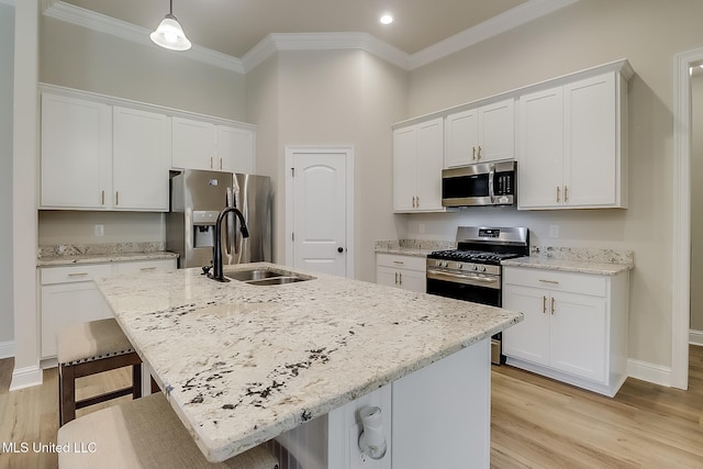 kitchen with hanging light fixtures, a center island with sink, white cabinets, and stainless steel appliances