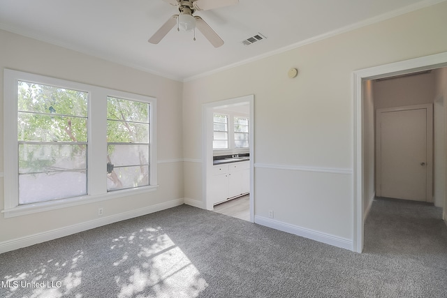 carpeted empty room with ceiling fan, crown molding, and a wealth of natural light