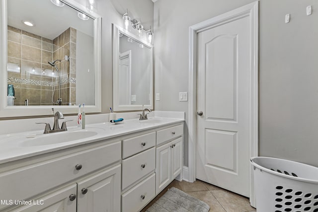 bathroom featuring double vanity, a tile shower, a sink, and tile patterned floors