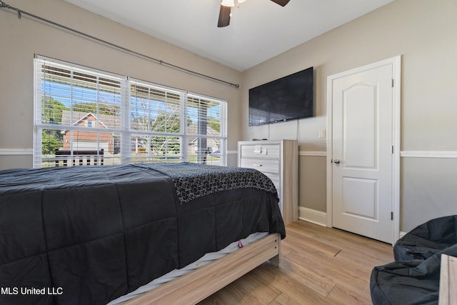 bedroom with light wood finished floors, baseboards, and a ceiling fan