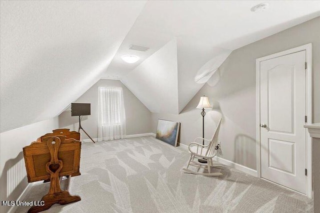 sitting room featuring light carpet, vaulted ceiling, visible vents, and baseboards