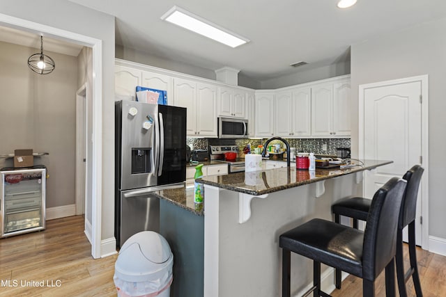 kitchen featuring white cabinets, dark stone counters, stainless steel appliances, and backsplash