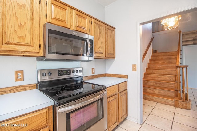 kitchen featuring light tile patterned flooring, appliances with stainless steel finishes, and a notable chandelier