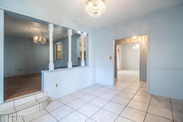 tiled empty room featuring an inviting chandelier