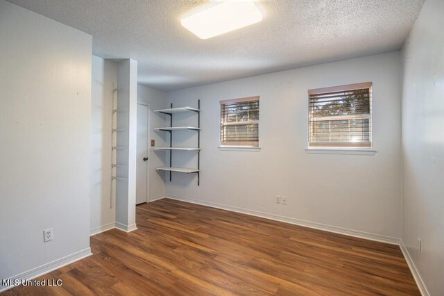 unfurnished room featuring dark hardwood / wood-style floors and a textured ceiling