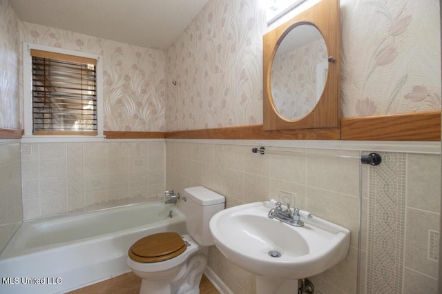 bathroom with tile walls, sink, a bathtub, and toilet