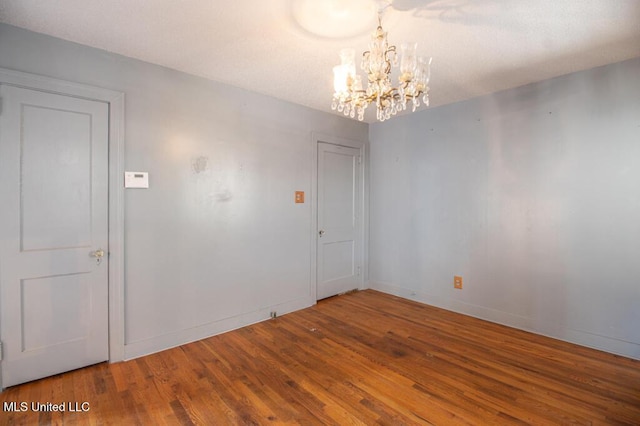 unfurnished room with wood-type flooring and a notable chandelier