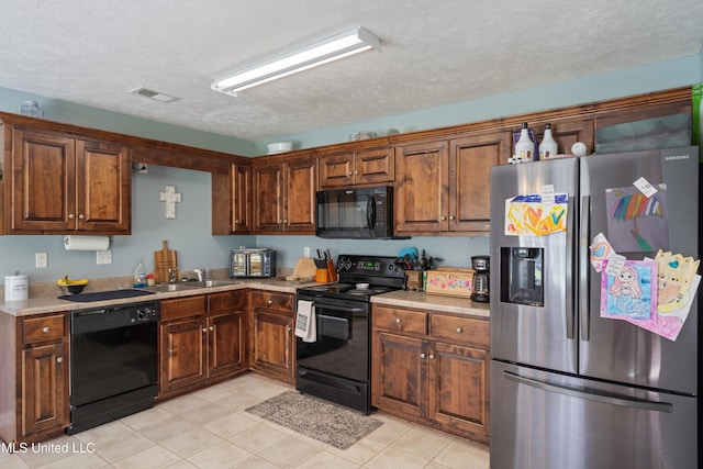 kitchen with black appliances, a textured ceiling, light countertops, a sink, and light tile patterned floors