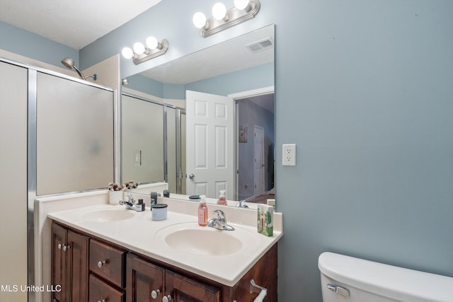 bathroom featuring toilet, a shower stall, and double vanity