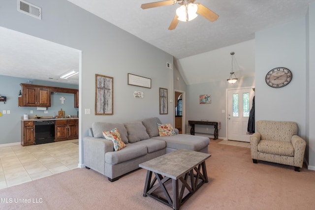 living area with light colored carpet, ceiling fan, baseboards, light tile patterned floors, and vaulted ceiling