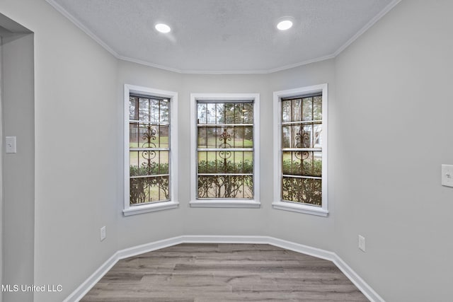 empty room with a textured ceiling, wood finished floors, and baseboards